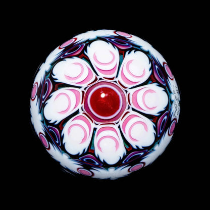 Handcrafted glass marble with red center, intricate pink and white floral pattern