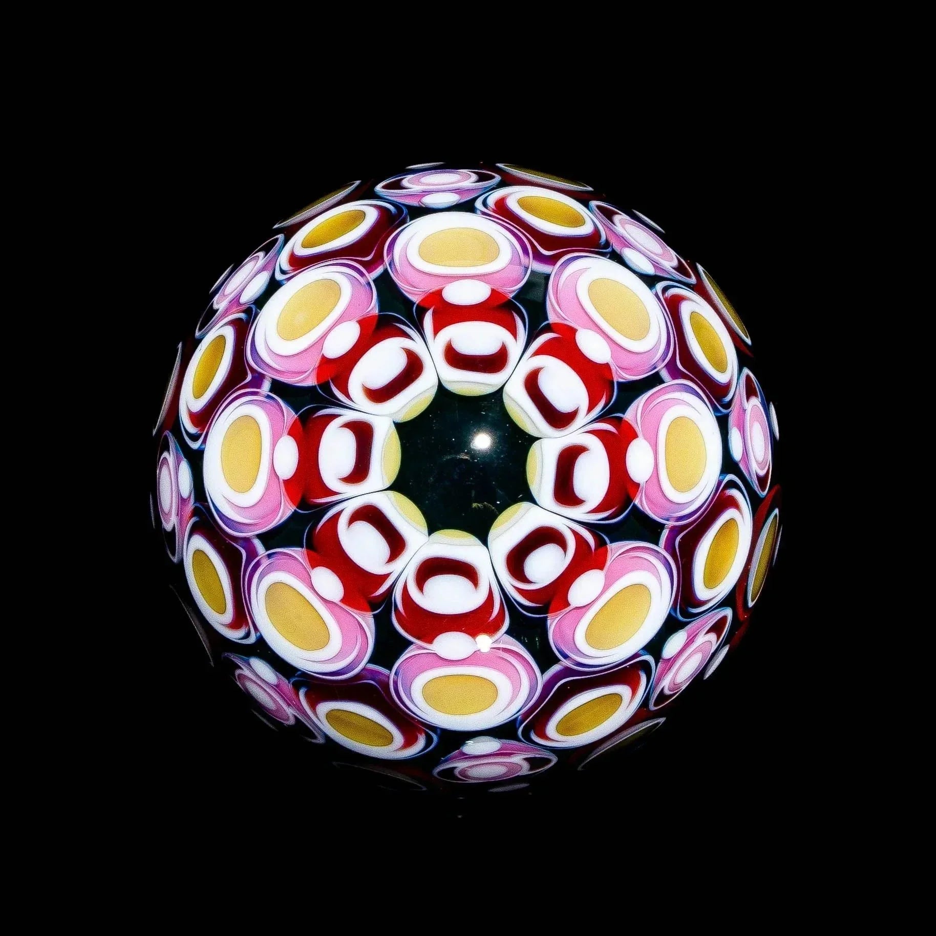 Colorful heady glass marble featuring intricate cane patterns on a black background