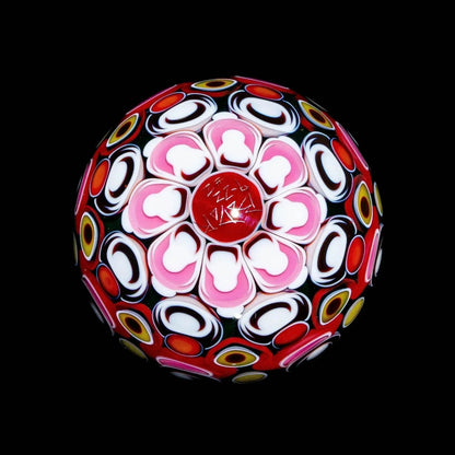 Colorful glass marble with intricate flower and geometric patterns on black background