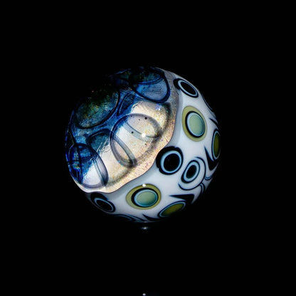 Heady glass marble with blue and green circle patterns on a black background