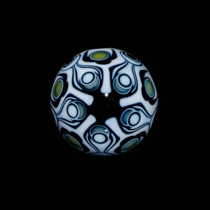 Heady glass marble with intricate black, white, and green geometric patterns on a black background
