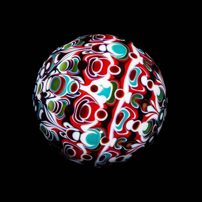 Colorful heady glass marble with intricate red, green, and white patterns on black background