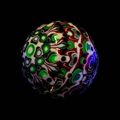 Heady glass marble with vibrant green, white, and red abstract patterns on black background