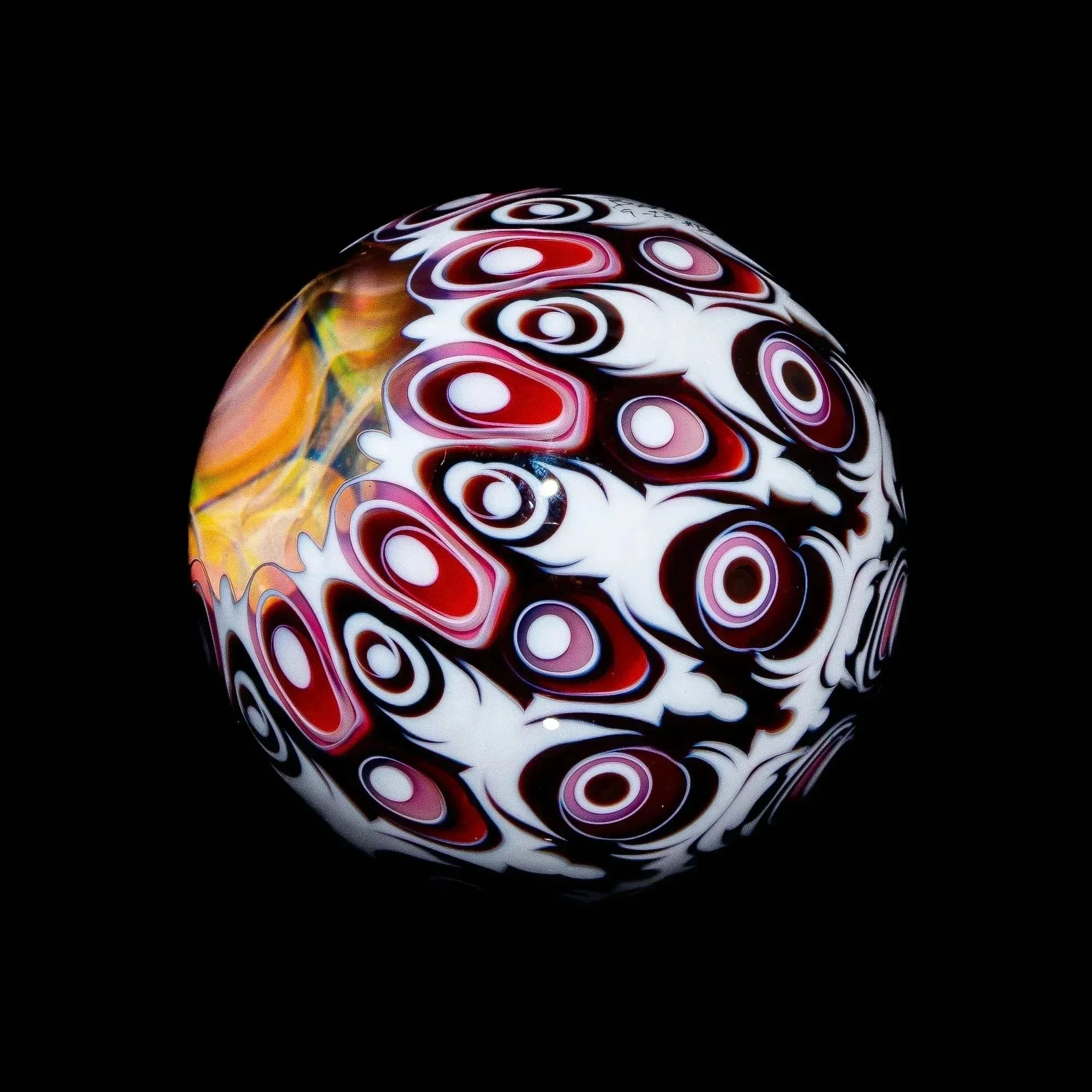 Heady glass marble with vibrant red, white, and black psychedelic patterns on black background