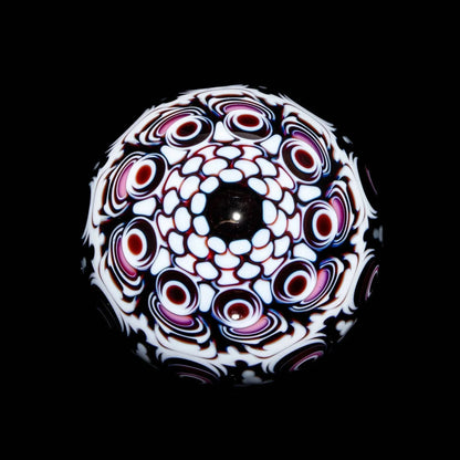 Intricate glass marble with black, white, and red psychedelic patterns on a black background