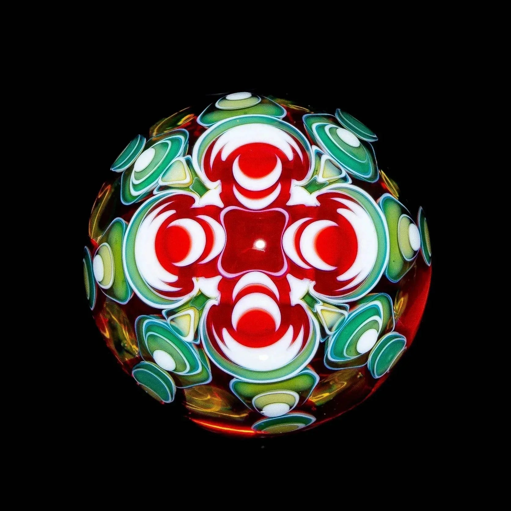 Heady glass marble with intricate red, white, and green patterns against black background