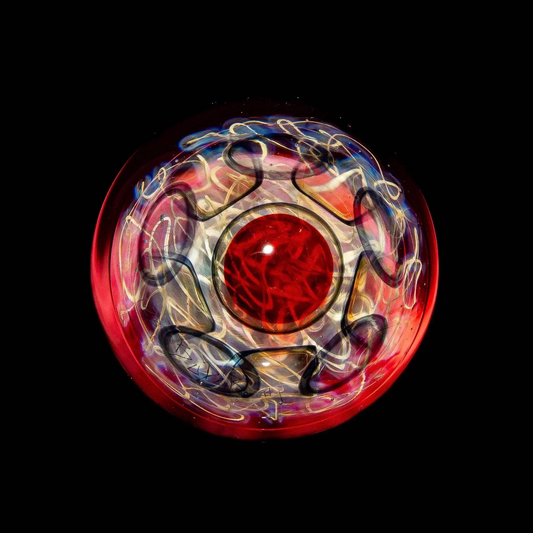 Heady glass marble with red core and intricate swirling patterns, displayed on black background.