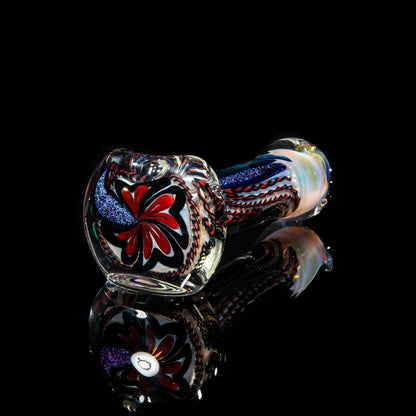 Handblown glass spoon pipe with red, blue, and white swirling patterns on black background