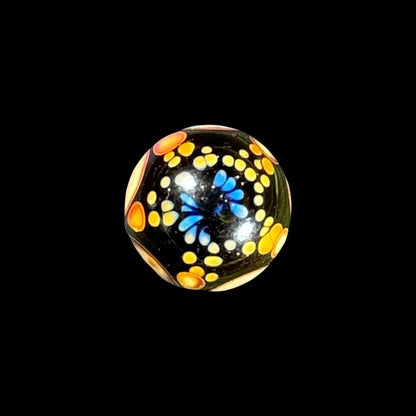 Heady glass marble with blue, yellow, and orange dot patterns on a black background