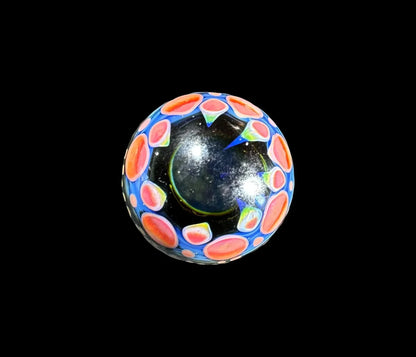 Handmade glass marble with vibrant red and blue accents on a black background