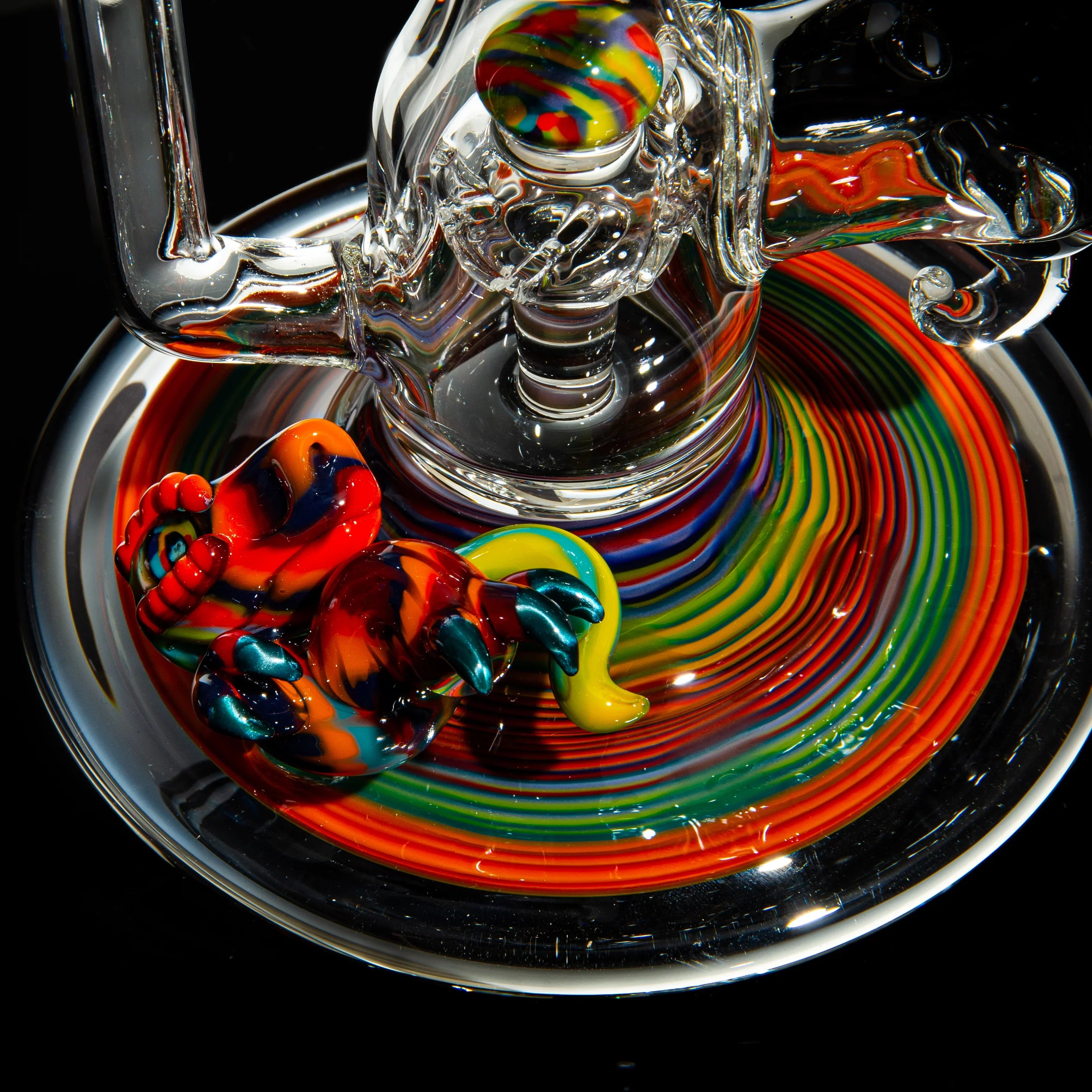 Colorful heady glass rig with vibrant rainbow swirl base and a sculpted glass figure