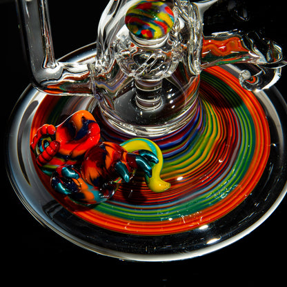 Colorful heady glass rig with vibrant rainbow swirl base and a sculpted glass figure