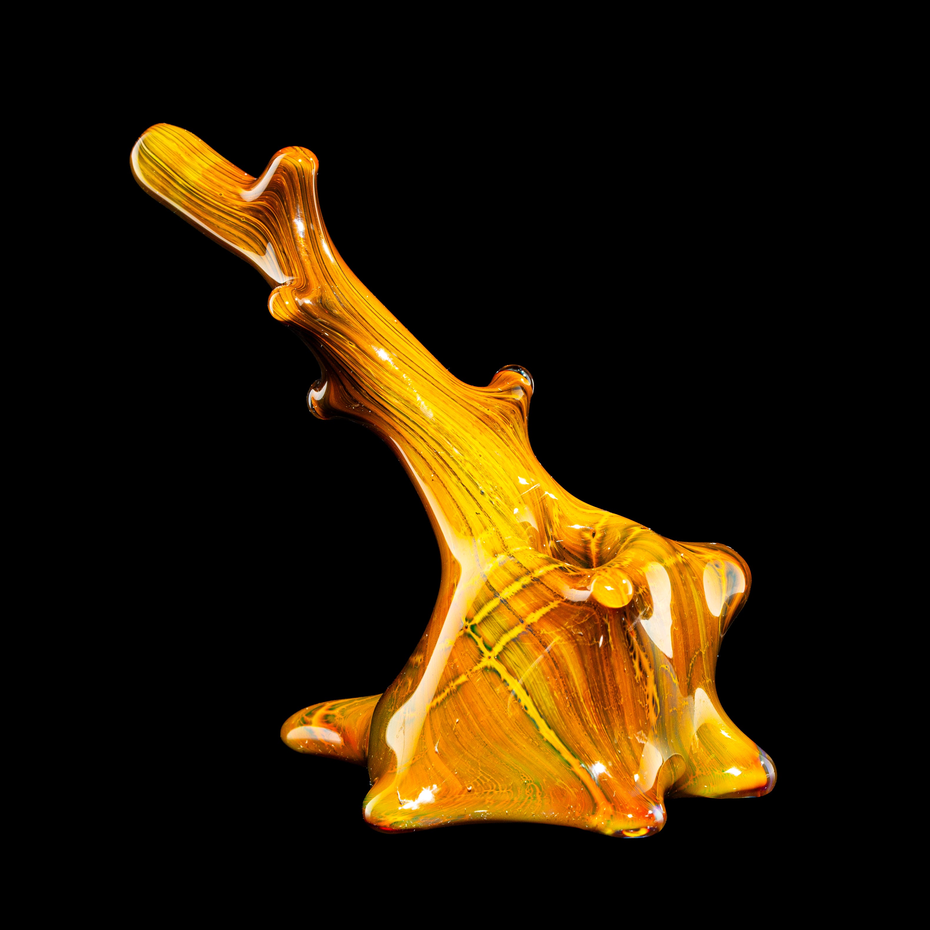 Heady glass art pipe in amber tones with organic, sculptural design on black background