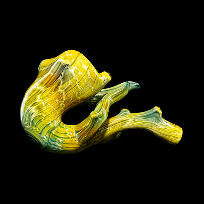 Hand-blown yellow and green glass pipe with wood grain texture on black background