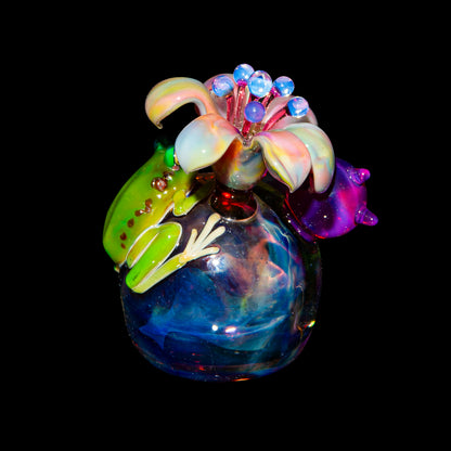 Colorful glass art piece with a green frog and flower detail against a black background