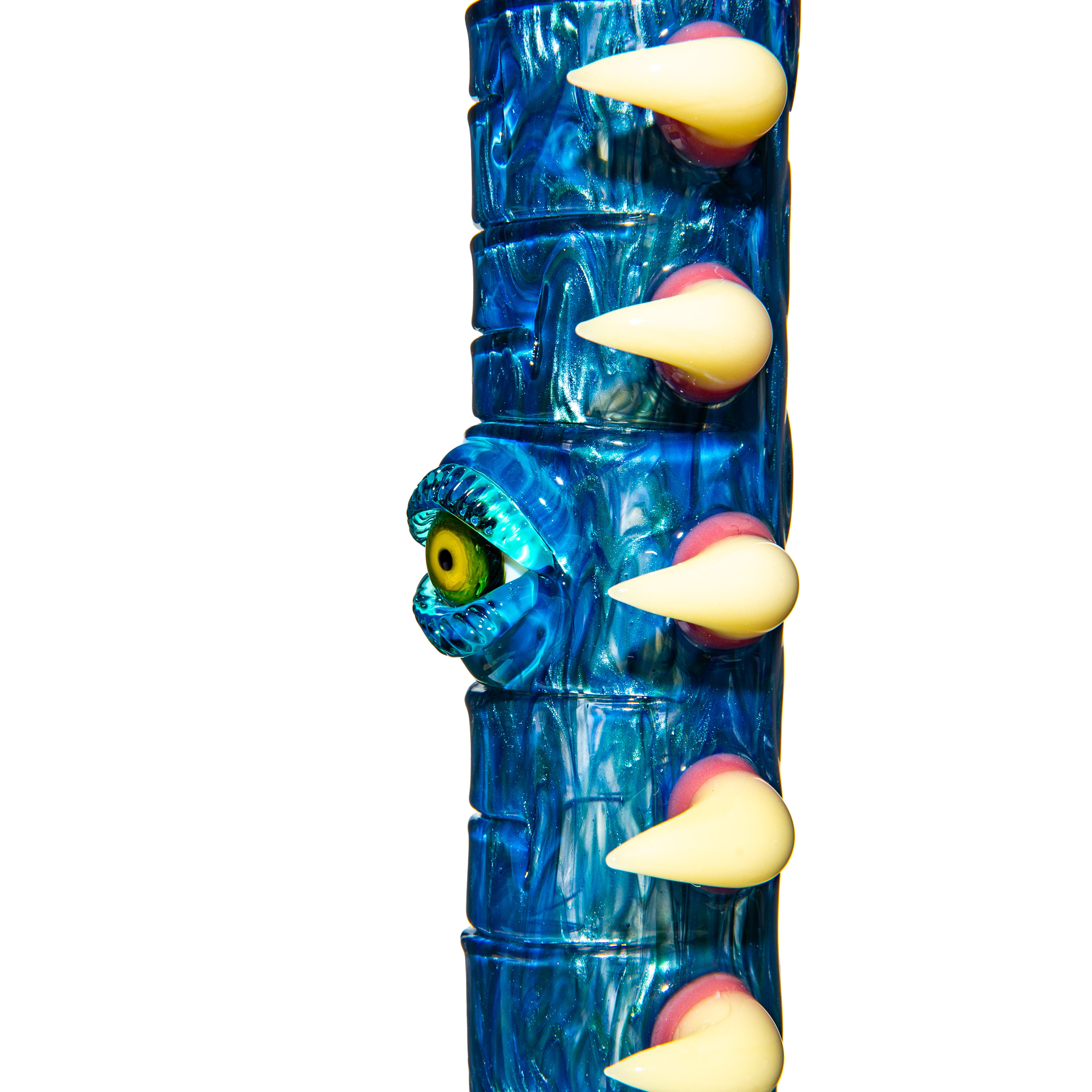 Close-up of a blue glass water pipe with a sculpted yellow eyeball and white spikes