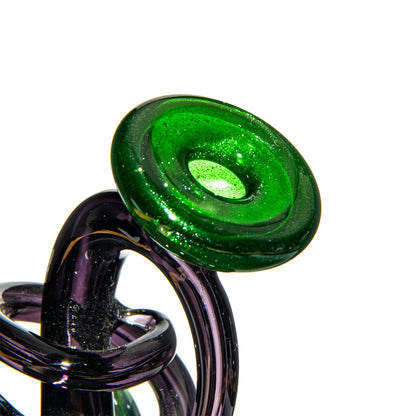 Close-up of a green and purple artisan glass smoking pipe with intricate design