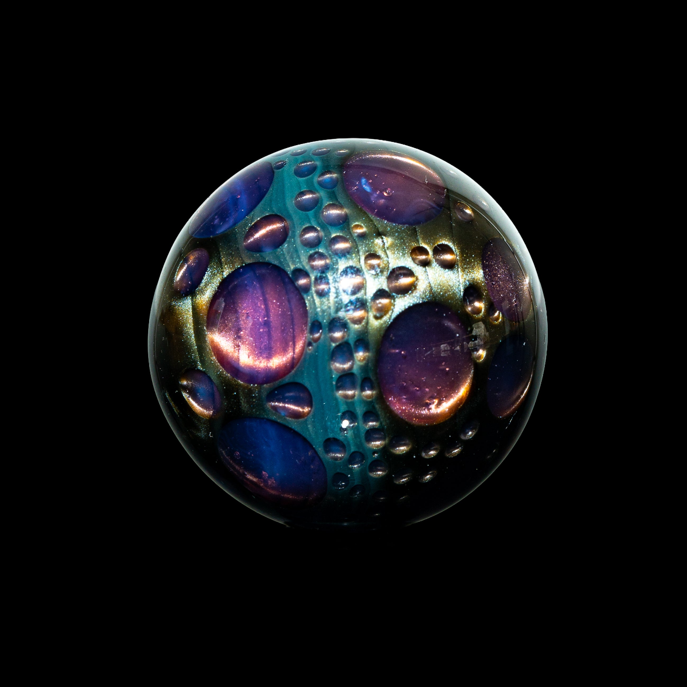 Handcrafted glass marble with colorful bubble patterns on a black background