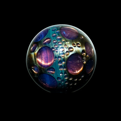 Handcrafted glass marble with colorful bubble patterns on a black background