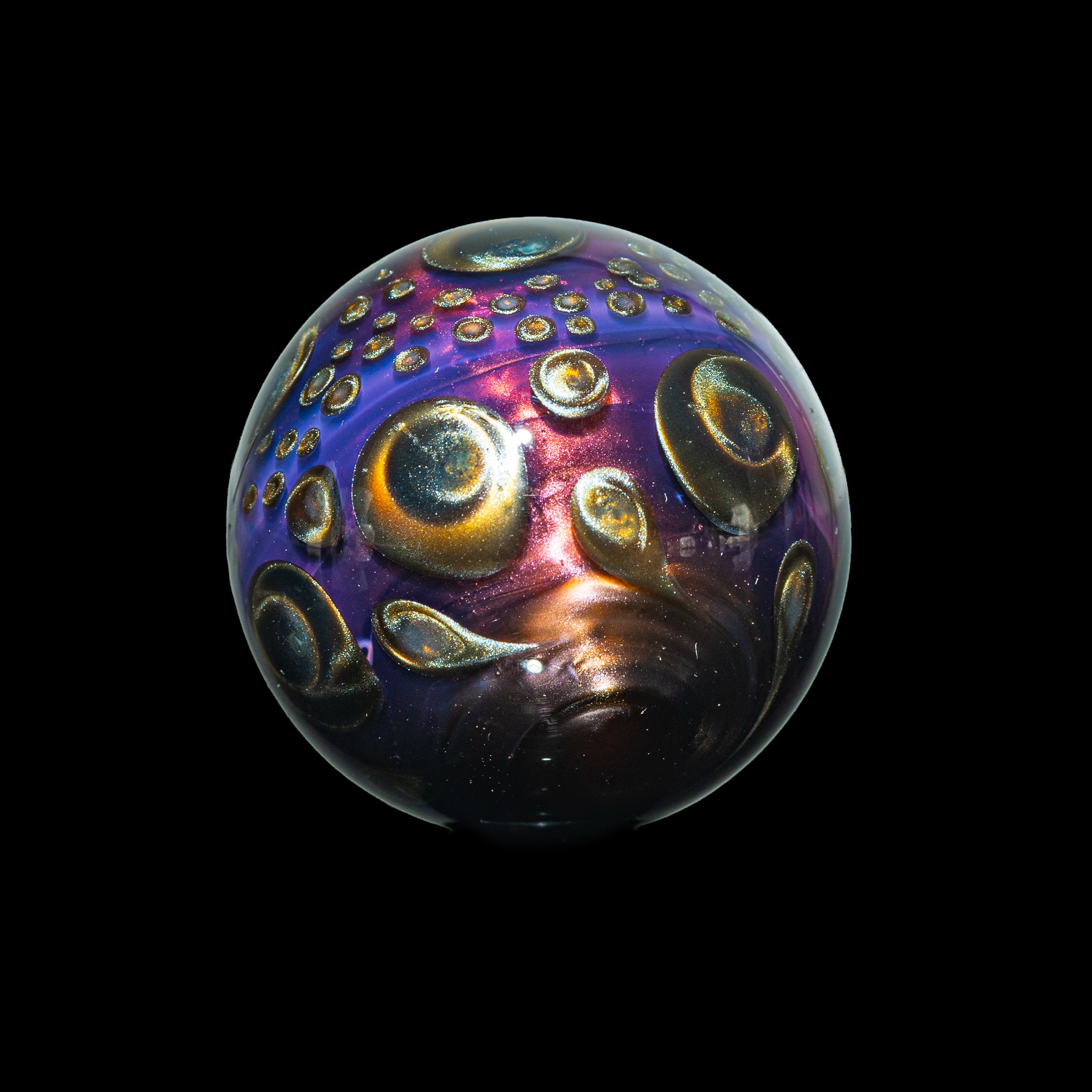 Colorful heady glass marble with metallic swirls and bubble details on black background