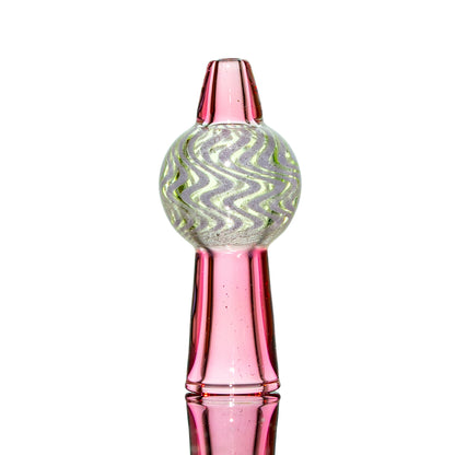 Pink glass carb cap with wavy green and white pattern, standing upright on white background.
