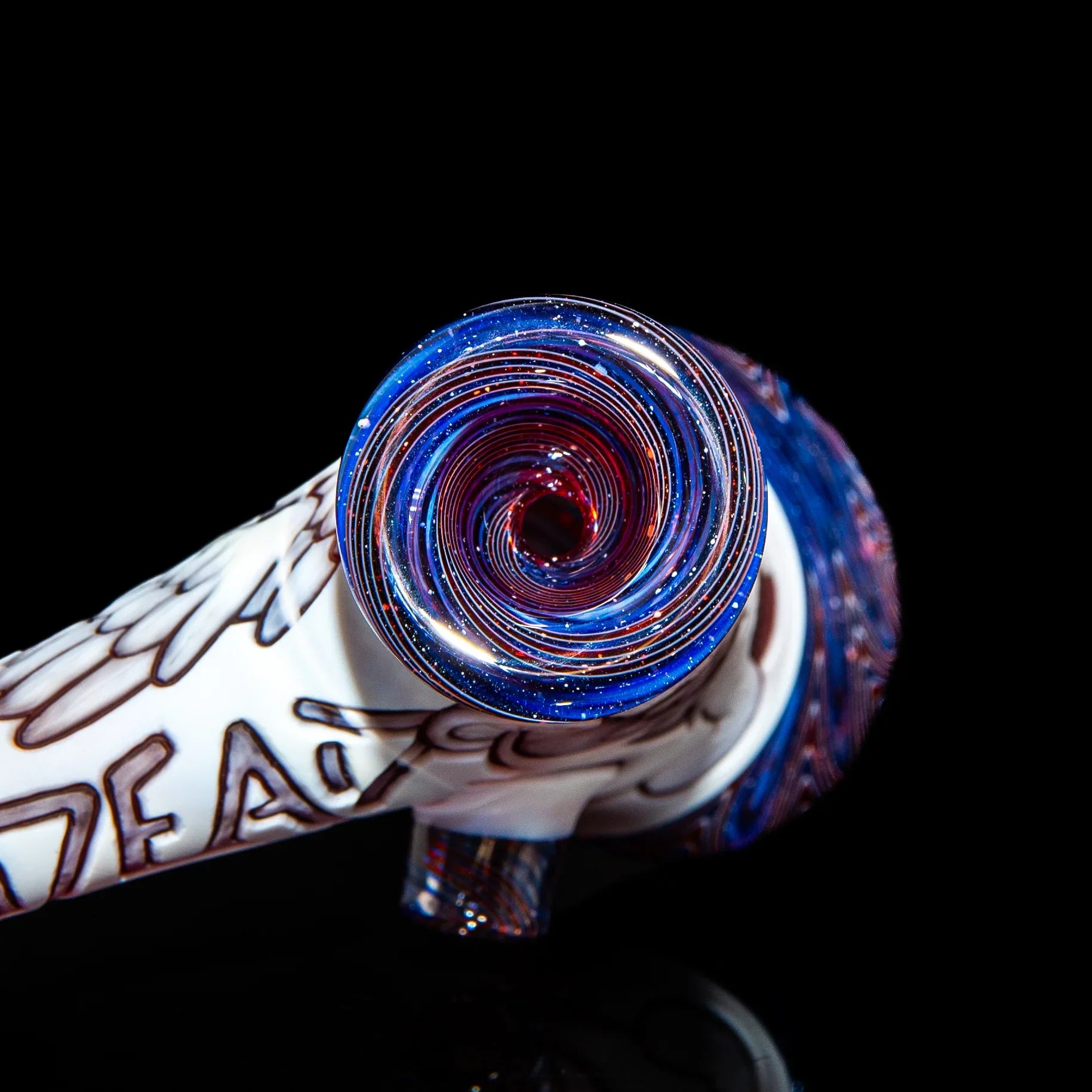 Glass hand pipe with blue, red, and white spiral design on black background