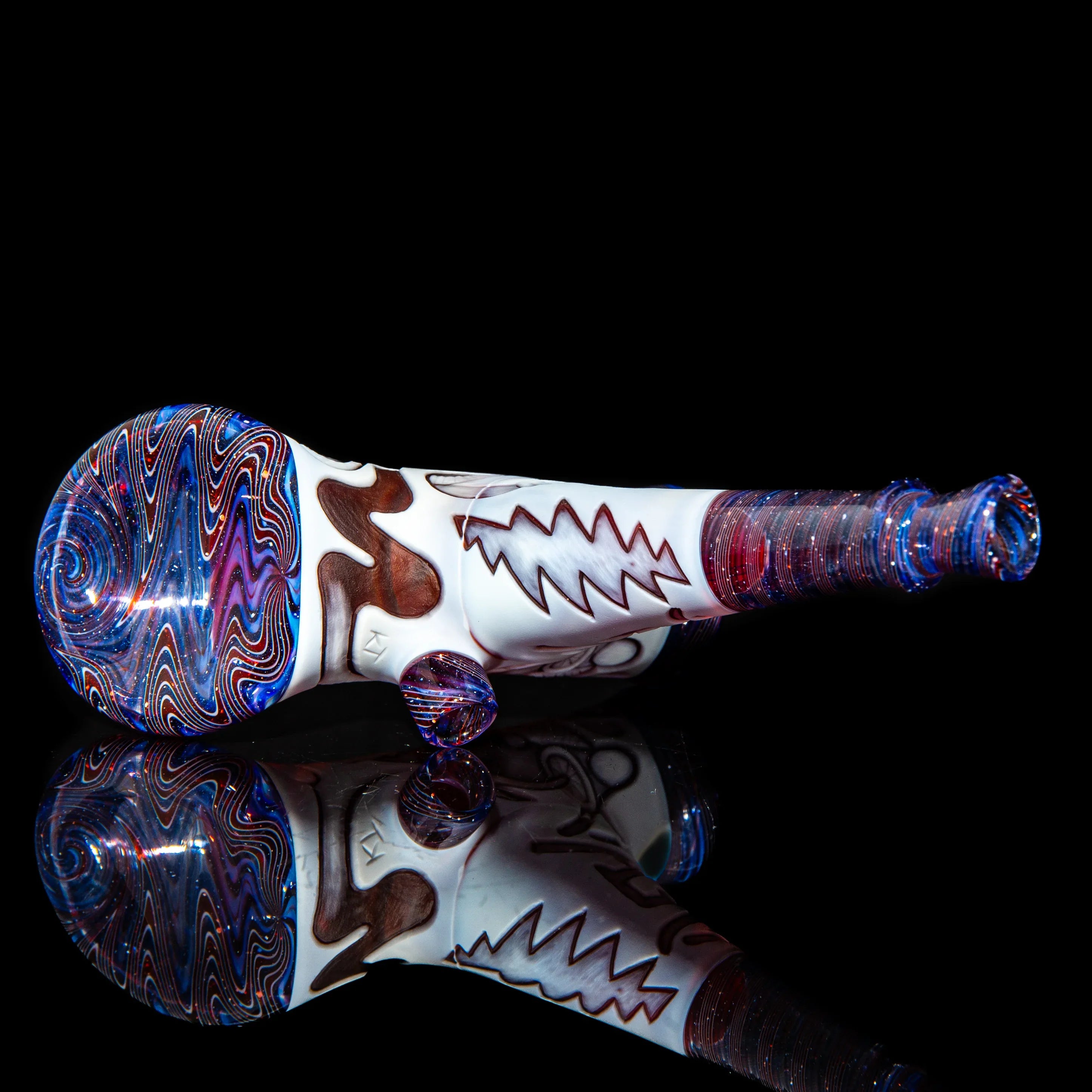 Heady glass hand pipe with colorful swirl patterns and zigzag design on black background