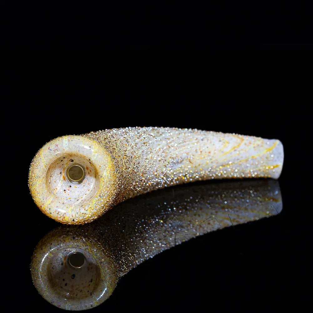 gold-flecked glass smoking pipe shaped like a horn on a reflective black surface