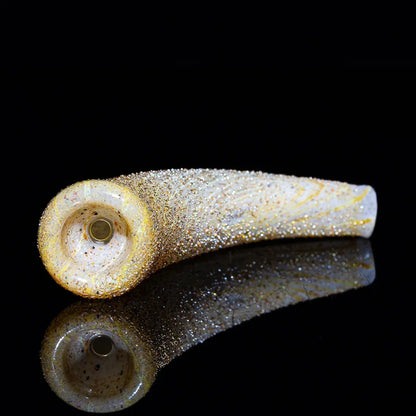 gold-flecked glass smoking pipe shaped like a horn on a reflective black surface