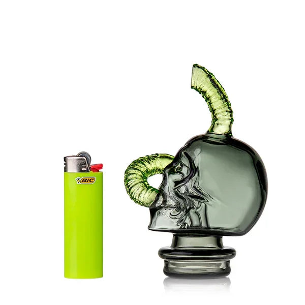 Glass skull water pipe with green horns beside lime green lighter on white background