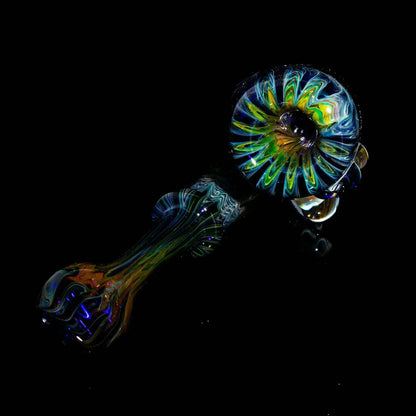 Colorful glass hand pipe with skull design on black background