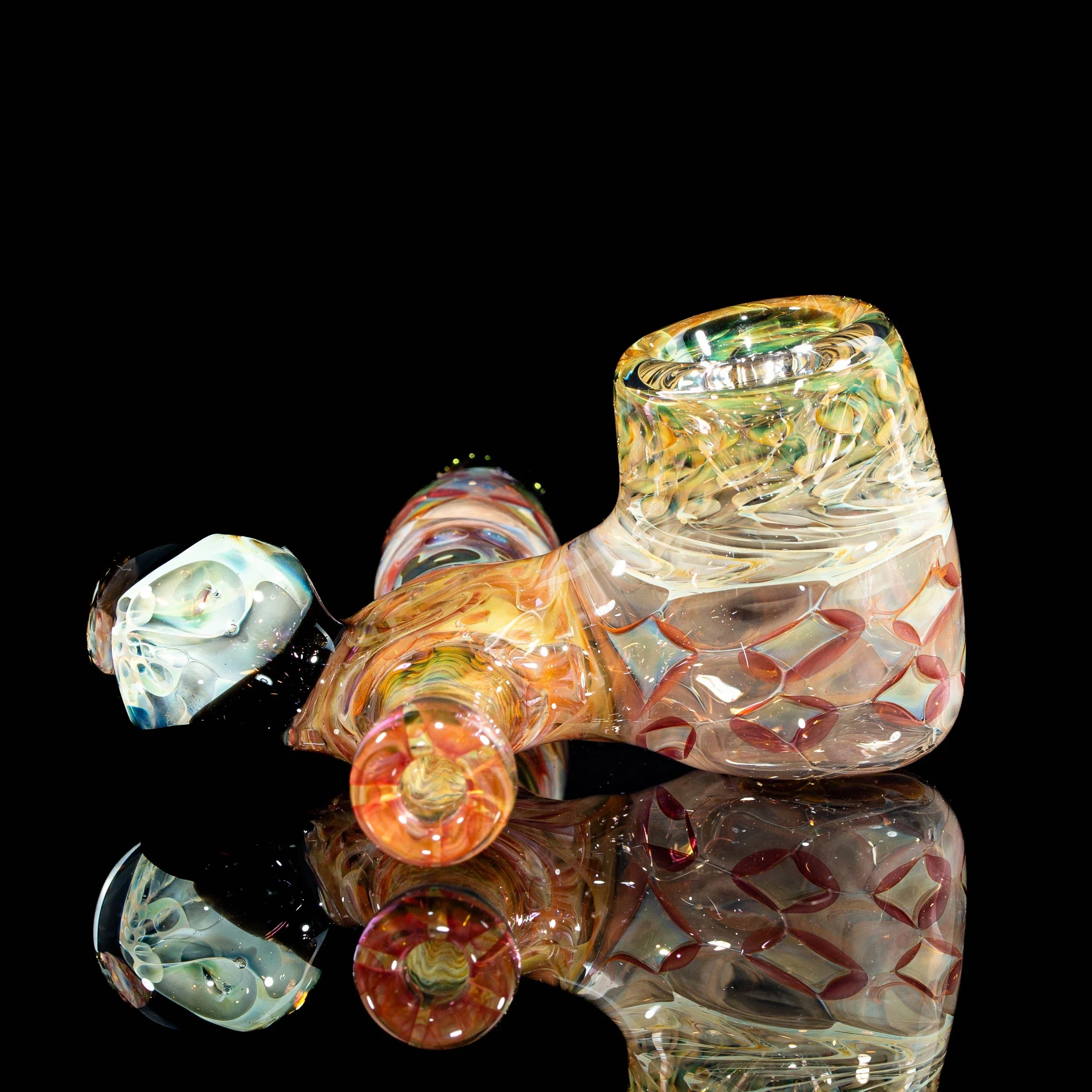 Colorful hand-blown glass smoking pipe with intricate patterns on a black reflective surface