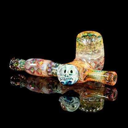 Colorful hand-blown glass pipe with intricate designs and a skull accent on black background