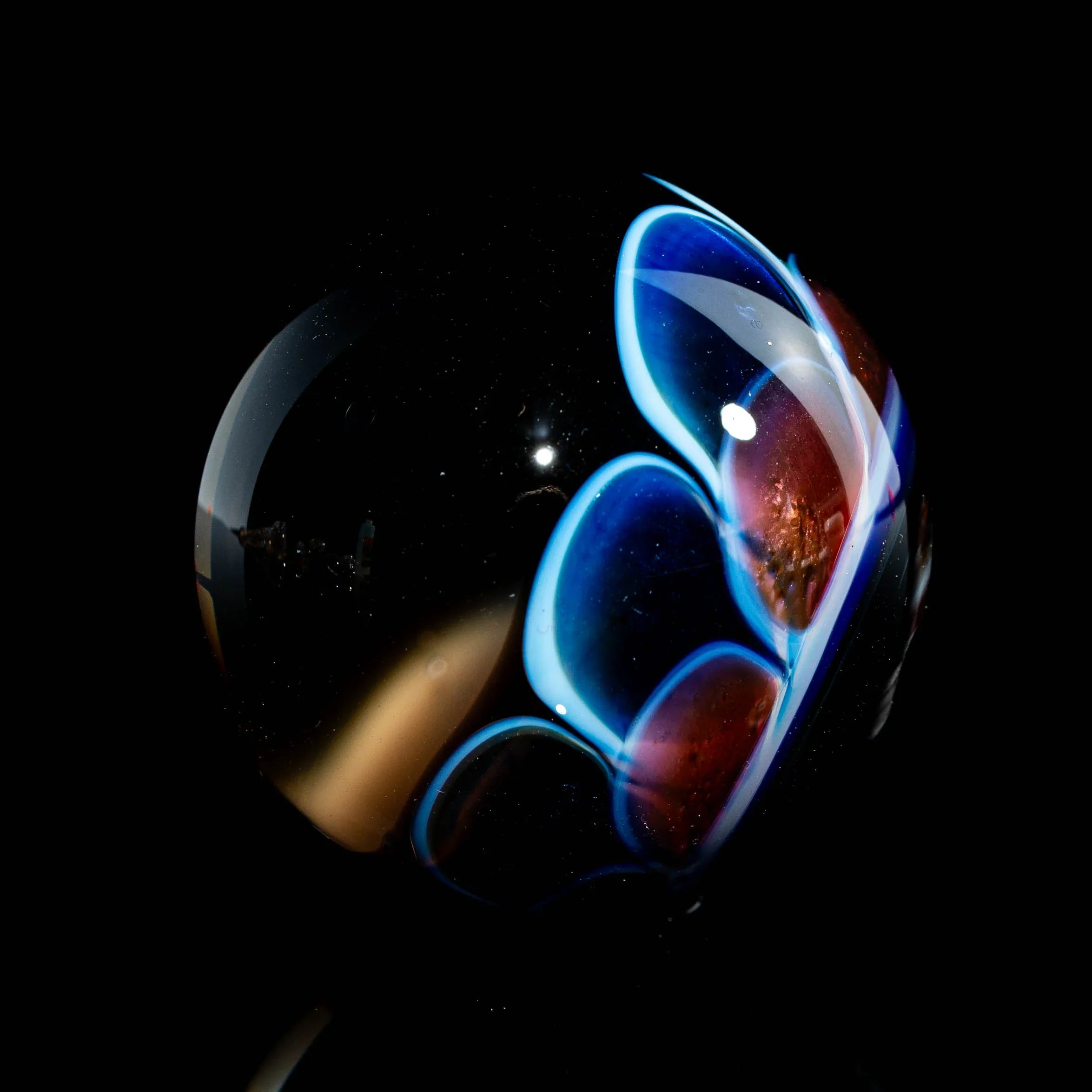 Heady glass marble with blue and red flame-like patterns on a black background