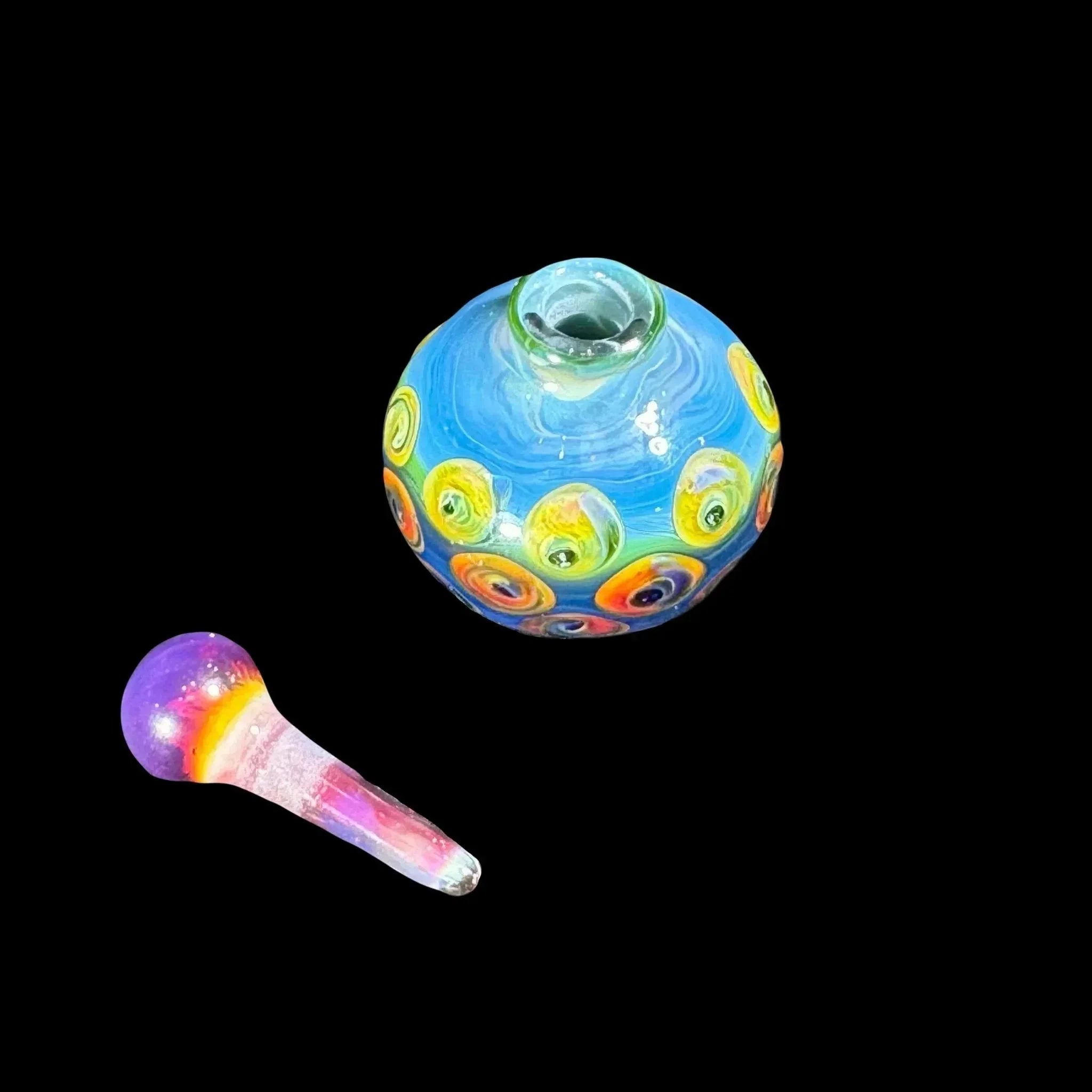Colorful glass carb cap and dab tool with blue, yellow, and rainbow swirl designs on black background