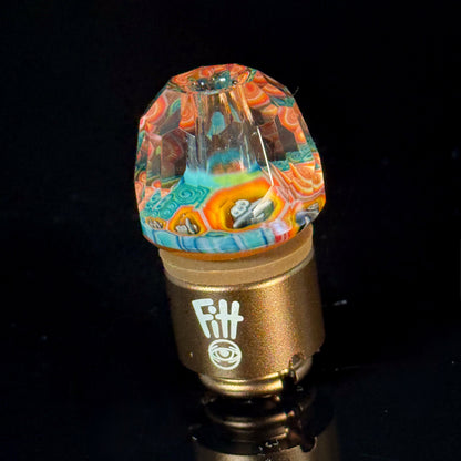 Colorful faceted glass carb cap with intricate patterns on a gold base for vaporizers.