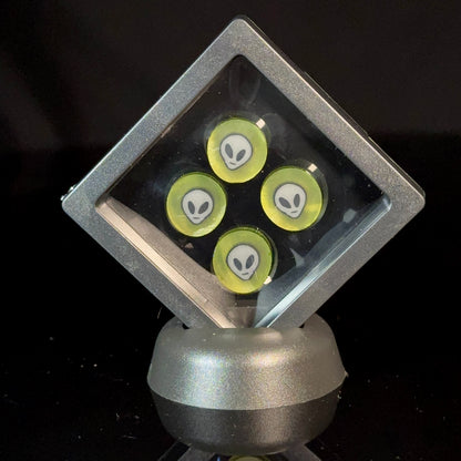 Glass marbles with alien face designs in a display case, black background
