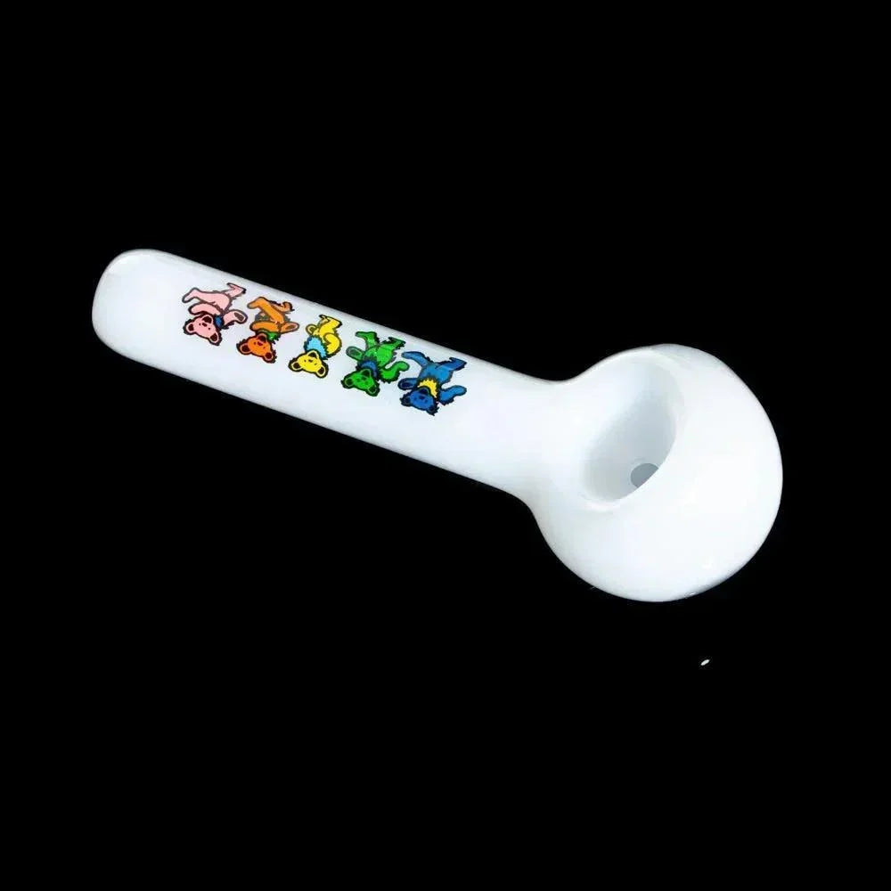 White glass hand pipe with colorful dancing bear designs on the stem, isolated on black background.