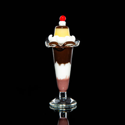 Glass sundae cap stand with layered colors and a cherry detail on black background