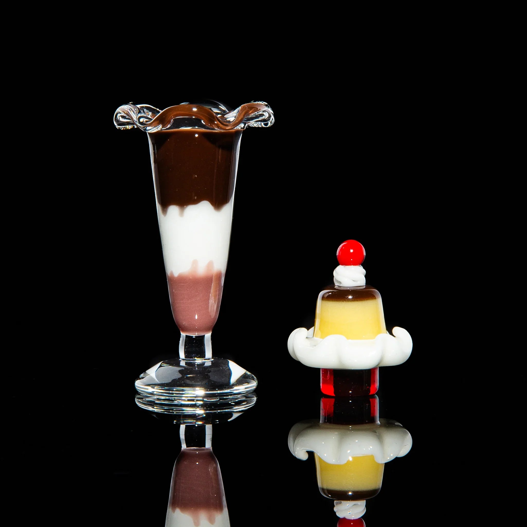 Dessert-themed glass carb caps for dab rigs, shaped like a parfait and pudding, on black background