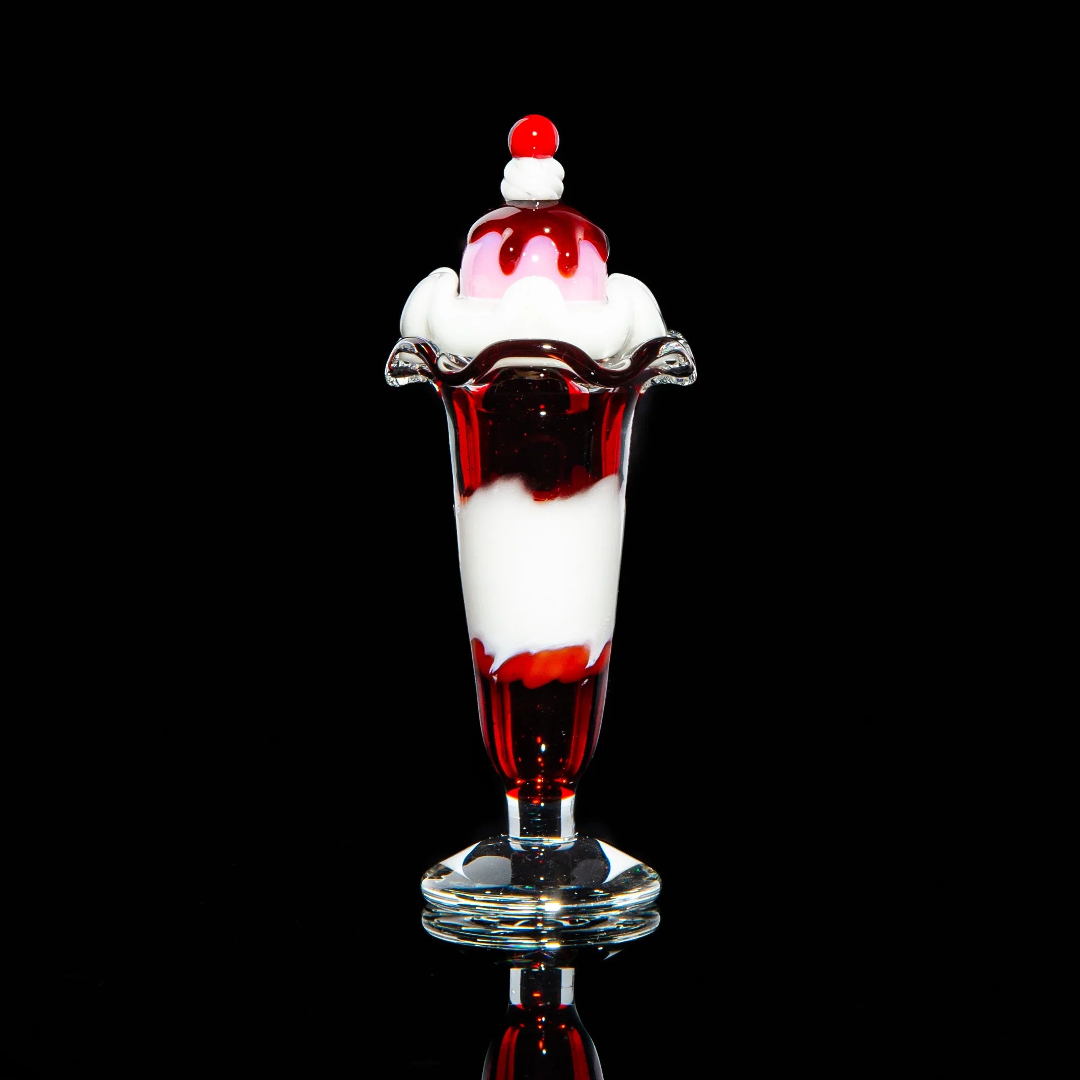 Glass sundae carb cap with red and white swirl, shaped like ice cream on black background.