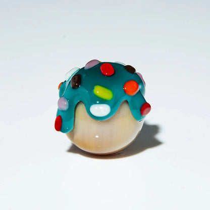Colorful glass marble with blue top and rainbow sprinkles on white background