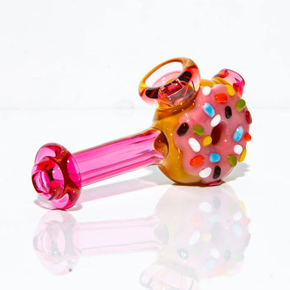 Colorful glass hammer pipe with pink donut and rainbow sprinkle design on white background
