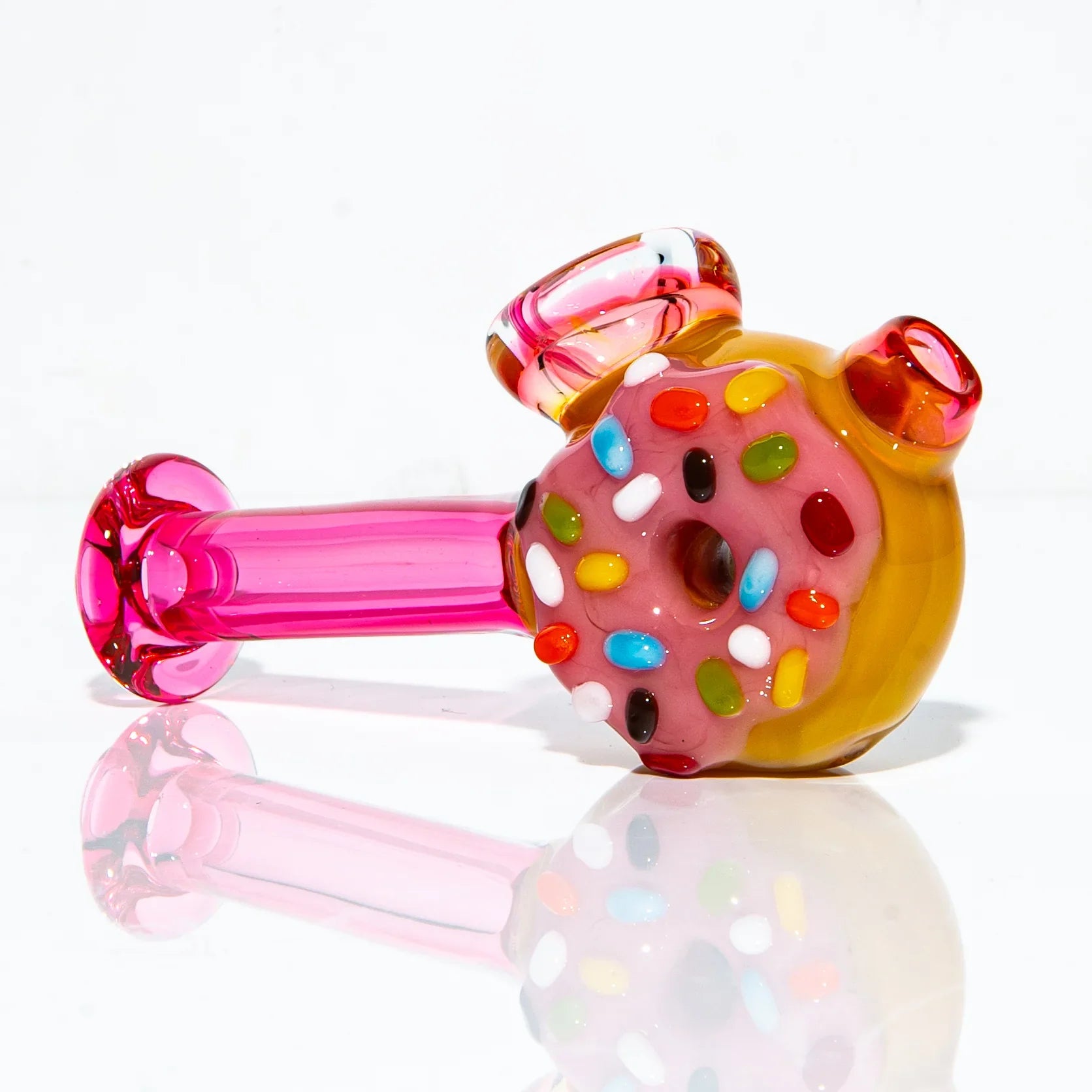 Hand-blown glass pipe shaped like a pink donut with rainbow sprinkles, vibrant colors.