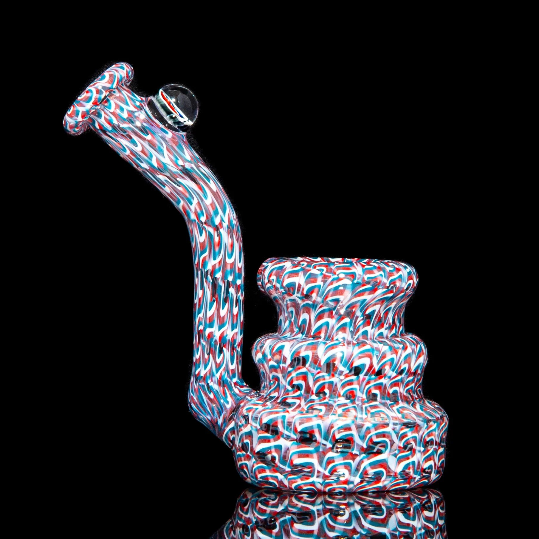 Colorful heady glass water pipe with red, white, and blue swirl patterns on black background