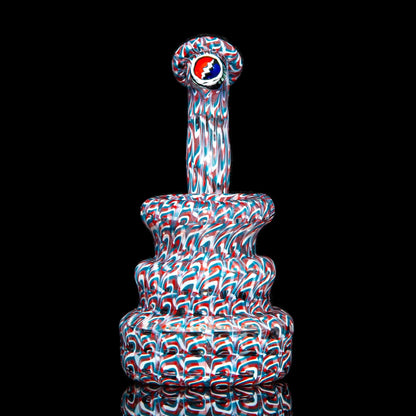 Heady glass water pipe with red, white, and blue pattern, round tiered base on black background