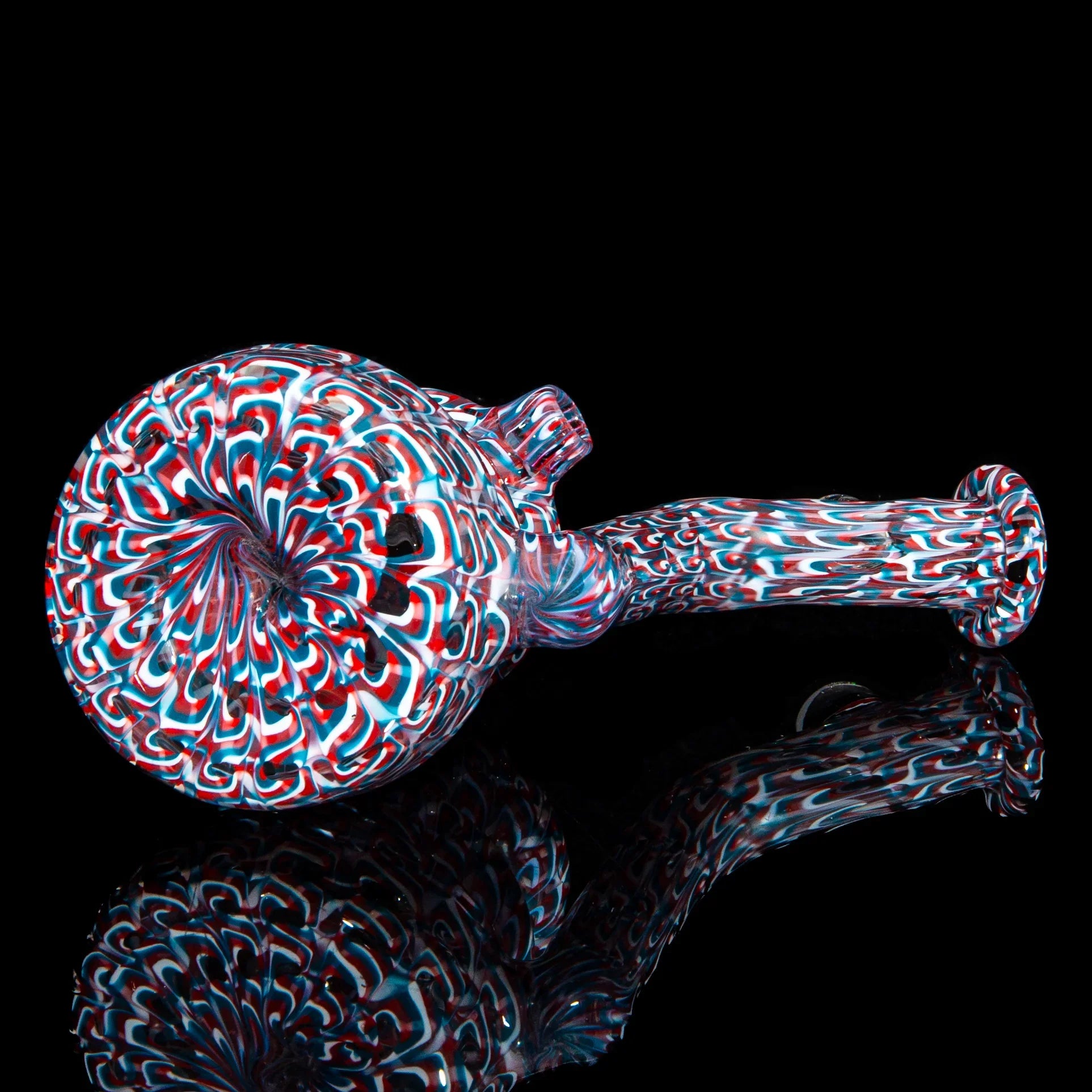 Colorful red, white, and blue glass hand pipe with intricate spiral patterns on black background.