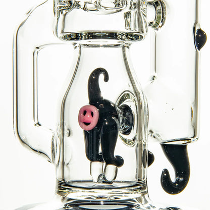 Close-up of a clear glass water pipe with a black glass figure and pink smiley face accent.