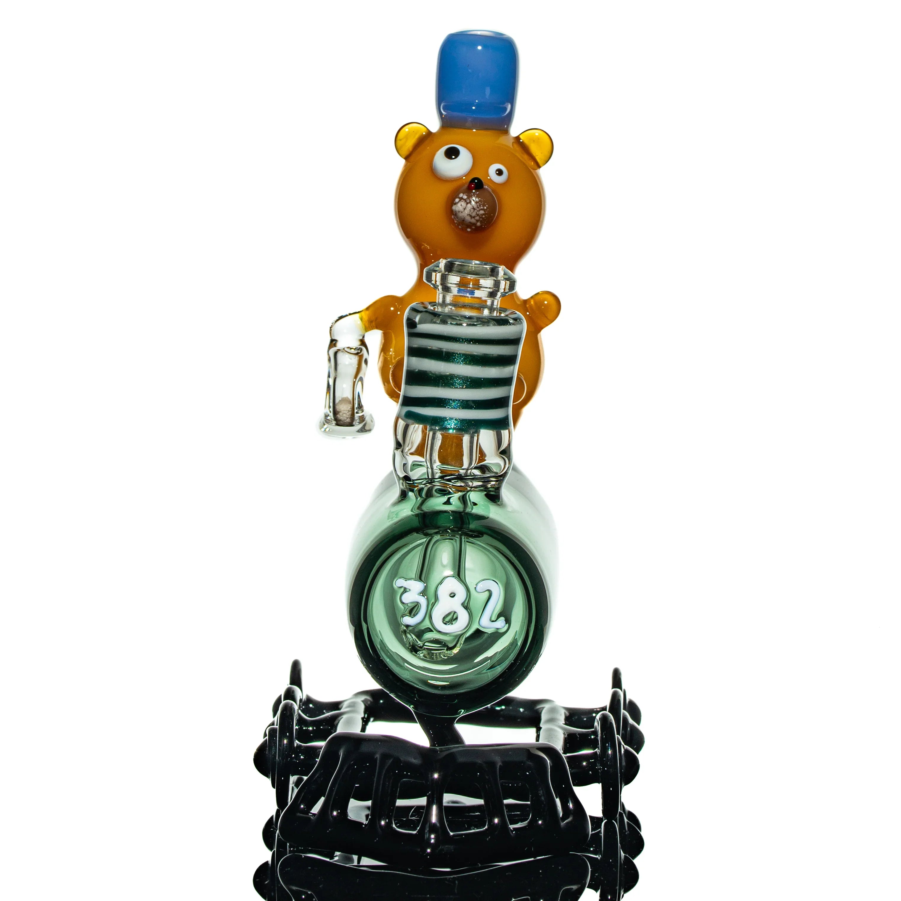 Heady glass pipe shaped like a train with a whimsical bear figure and blue hat, number 382.