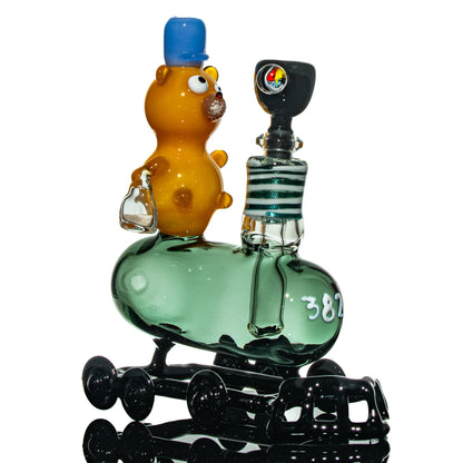 Artisan glass water pipe shaped like a train with a cartoon bear figure on top
